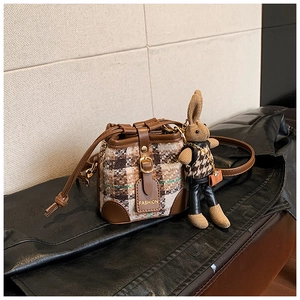 Detail of retro houndstooth bucket bag with brown leather trim and rabbit charm