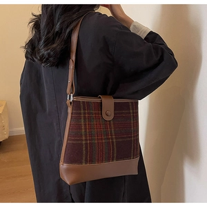 Détail du sac seau à carreaux rouges avec bandoulière en cuir et fermoir magnétique