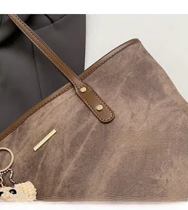 Detail of coffee tote bag with twill fabric texture, leather trim, and bear charm