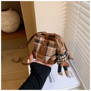 Detail of drawstring bucket bag with tweed fabric and cute bunny doll accessory