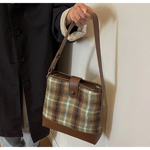 Détail du sac seau vintage avec lanières en cuir et tissu à carreaux écossais