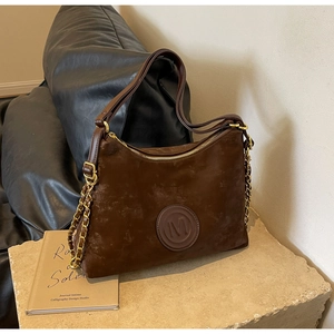 Detail of vintage brown tote bag featuring embossed M logo and gold chain strap