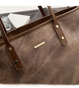 Close-up of brown textured tote bag with golden hardware and leather strap details