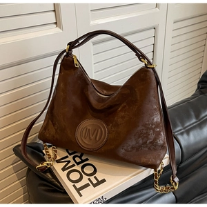 Close-up of a brown hobo bag with an embossed M logo and elegant gold metal hardware