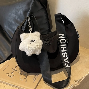 Black nylon hobo bag with fashion strap and star charm on urban stone background