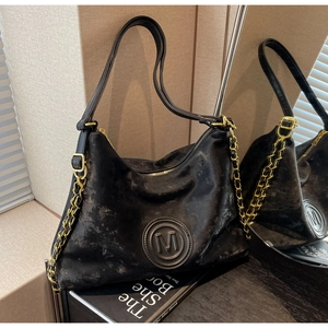 Detailed shot of retro black faux leather tote bag with M logo and gold chain strap