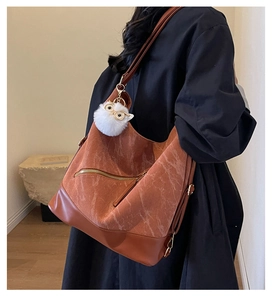 Detailed shot of brown corduroy tote bag with leather bottom and cute owl pompom charm