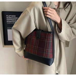 Détail du sac seau à carreaux rétro avec finitions cuir sur un trench-coat beige