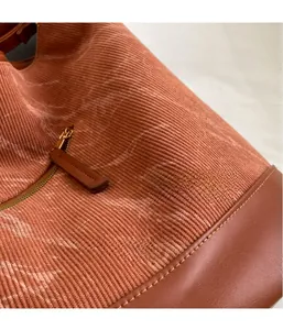 Detail of orange corduroy fabric texture with gold zipper and brown leather puller