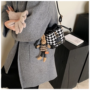 Detail of houndstooth bucket bag with leather trim and decorative bunny charm accessory