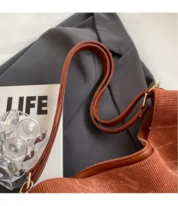 Detailed close-up of brown corduroy tote bag with adjustable strap and gold metal buckle
