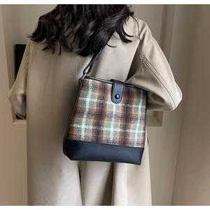 Sac seau classique à carreaux verts avec garniture en cuir noir porté sur un manteau