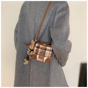 Detail of a mini plaid crossbody bag with leather trim and cute rabbit plush charm