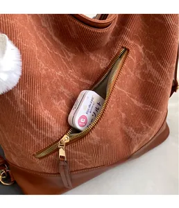 Detail of corduroy tote bag showing front zipper pocket and soft white pompom charm