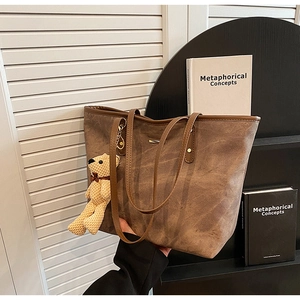 Detail of brown tote bag with vintage canvas texture and a beige teddy bear charm