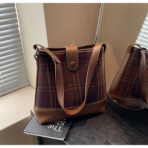 Détail du sac seau vintage en cuir marron avec des empiècements à carreaux foncés