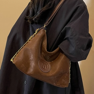 Brown vintage leather tote bag with gold chain straps shown on black coat model
