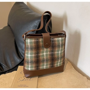 Détail du tissu en tweed à carreaux vert et marron avec garniture en cuir sur le sac seau