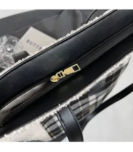 Detailed macro view of gold metal zipper and plaid tweed texture on a winter tote bag