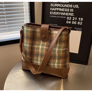 Détail du sac seau à patchwork écossais avec sangle en cuir marron et fermoir magnétique