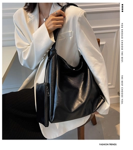 Schicke große schwarze Hobo-Tasche aus weichem Leder getragen zum weißen Blazer