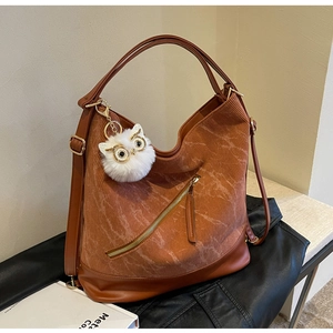 Detail of brown corduroy tote bag showing zipper pocket and owl charm accessory