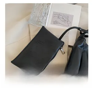 Nahaufnahme einer schwarzen Kunstleder-Tasche mit Metallreißverschluss auf hellem Dekor