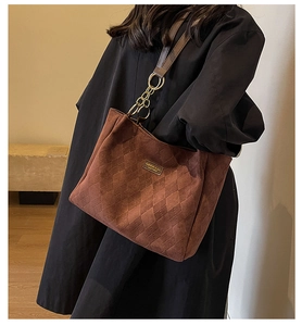 Close-up of brown suede tote bag with quilted diamond pattern and metal logo