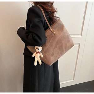 Detail of vintage brown tote bag with textured leather and a cute knitted bear charm
