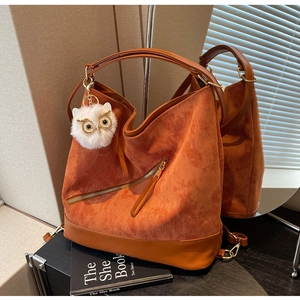 Detail of orange corduroy tote with diagonal zipper and cute owl plush keychain