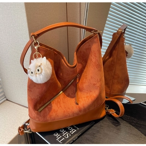 Detail of orange-brown corduroy tote bag with leather straps and owl pendant charm