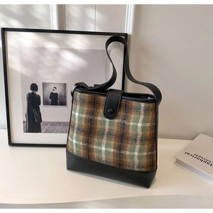 Détail du sac cabas vintage en tweed marron-vert avec finitions en cuir noir élégant