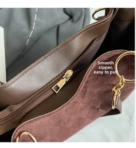 Detail of smooth gold zipper and diamond quilted suede texture on brown tote bag