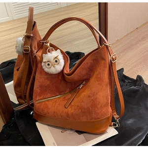 Close-up of caramel corduroy tote bag with white plush owl charm and leather trim
