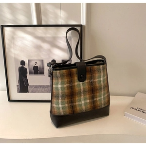 Détail du sac seau vintage avec tissu à carreaux et bandoulière en cuir noir de qualité