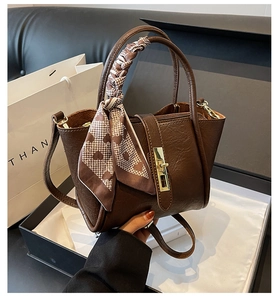 Macro view of retro brown bucket bag featuring fine pebble leather and elegant silk scarf