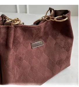 Detail of brown faux suede tote with diamond quilted texture and gold metal ring
