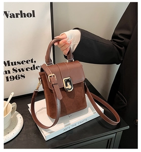 Close-up of vintage brown suede crossbody bag with gold metallic twist lock and handle