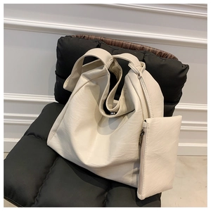 Detailansicht großer cremefarbener PU-Leder Shopper mit kleiner Tasche auf schwarzem Stuhl