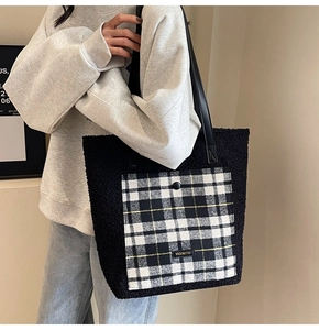 Close-up of fluffy black tote bag featuring a contrast black and white plaid pocket