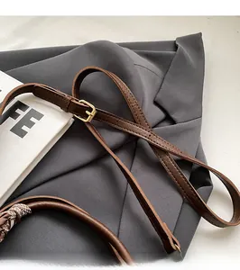Detail of a brown leather adjustable shoulder strap with a golden metal buckle for handbags