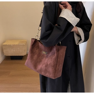 Detail view of burgundy tote bag with quilted diamond pattern and chain strap link