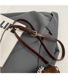 Détail de la bandoulière réglable en cuir marron avec boucle argentée et chaîne métal
