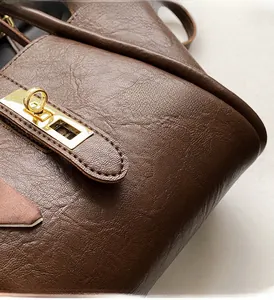 Detail of dark brown leather bucket bag showing soft texture and gold twist lock closure