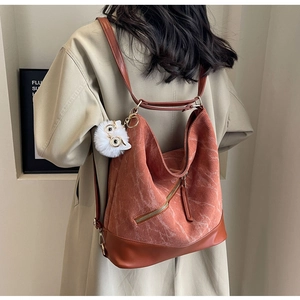 Detail view of orange corduroy tote bag featuring a leather base and owl charm