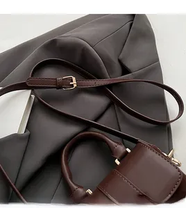 Detail of adjustable dark brown leather shoulder strap with gold buckle and stitching