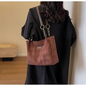 Close-up of vintage brown tote bag featuring quilted texture and chain leather strap
