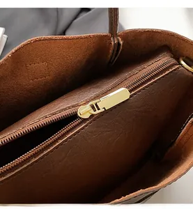 Close-up of smooth gold metal zipper and premium leather lining inside a brown bucket bag