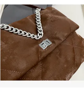 Gros plan d'un sac matelassé marron avec chaîne argentée et fermoir rotatif en métal