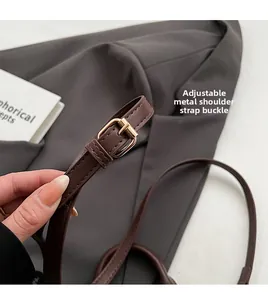 Detail of adjustable shoulder strap with golden metal buckle on brown leather bag